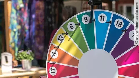 Ein Glücksrad in den Farben Rot, Grün, Gelb, Blau und Magenta und verschiedenen Zahlen