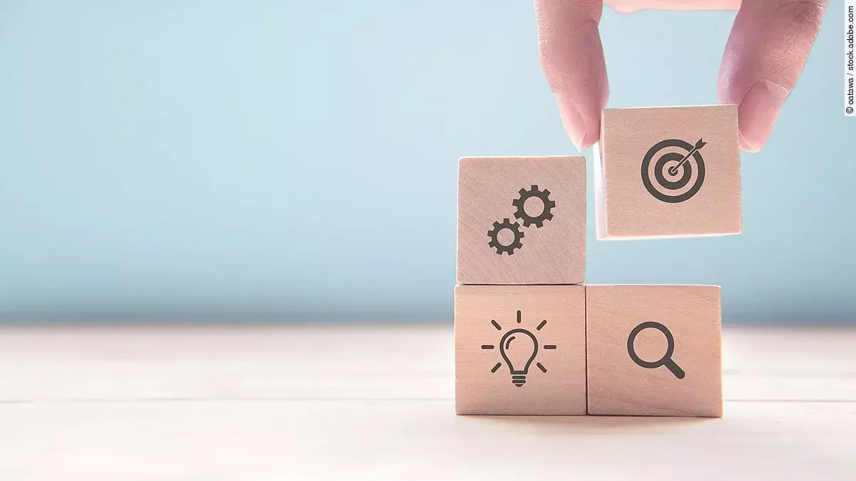 Ziel Hand stapelt Holzwürfel mit Strategiesymbolen darauf